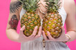 © LIGHTFIELD STUDIOS - cropped shot of young woman holding two ripe pineapples isolated on pink