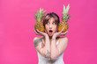 © LIGHTFIELD STUDIOS - surprised young woman holding ripe pineapples isolated on pink