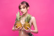 © LIGHTFIELD STUDIOS - beautiful young naked woman holding pineapples and looking at camera isolated on pink
