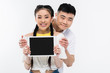© LIGHTFIELD STUDIOS - happy young asian couple showing digital tablet with blank screen and smiling at camera isolated on white