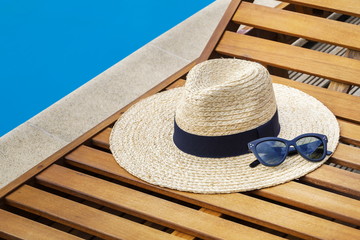 Straw hat with sunglasses near swimming pool