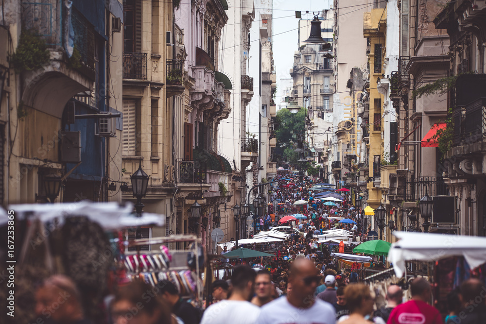 The narrow street of Buenos Aires is crowded with people. Shevelev. - obrazy, fototapety, plakaty 