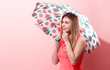 Happy Young Woman Holding An Umbrella On A Pink Background