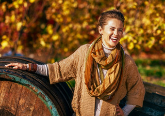 Wall Mural - Portrait of smiling young woman near wooden barrel in autumn out