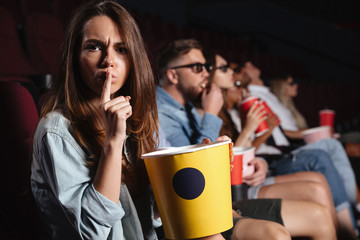 Poster - Lady sitting in cinema showing silence gesture.