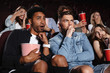 © Drobot Dean - Scared young friends sitting in cinema watch film