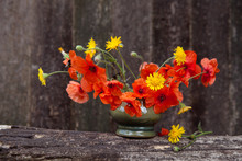 Red Poppies In A Green Vase On A Background Of A Wooden Texture Background