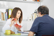 © Stocked House Studio - Smiling doctor nutritionist giving fruit to male patient sitting at the desk