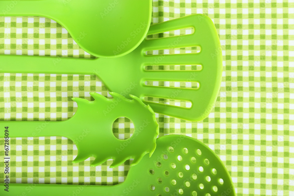 Green utensils on gingham textile background