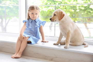 Wall Mural - Cute child with labrador retriever on window sill at home