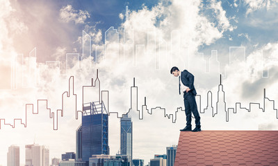 Businessman looking down from roof and modern cityscape at backg