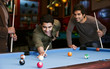 © IndiaPix - Young man aiming at cue ball while friends standing by pool table