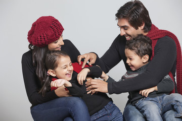 Wall Mural - Happy playful family sitting over grey background 