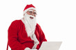 © IndiaPix - Happy Santa Claus listening to music while using laptop over white background
