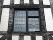 leaded glass window in a half timbered medieval type building with black oak beams and white plaster walls