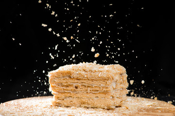 Poster - close-up delicious French Napoleon Cake of puff pastry with sour cream sprinkled crumbs on a wooden plate, selective focus