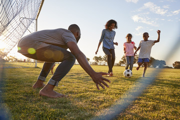 A boy kicks a football during a game with his family