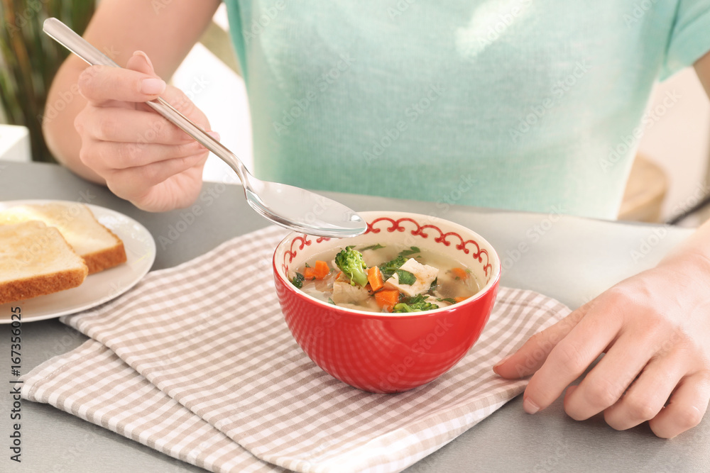 Woman eating homemade chicken soup on table
