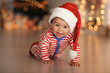 © Africa Studio - Cute little baby with Santa hat on floor and blurred Christmas lights on background