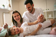 © liderina - Parents having fun with their little daughter on bed. Family spending time at the morning.