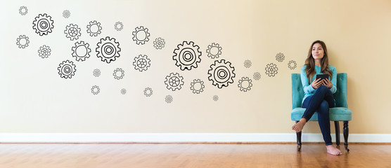 Wall Mural - Gears with young woman holding a tablet computer in a chair
