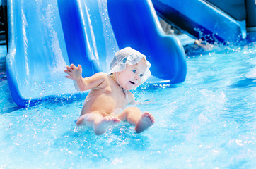 Small child in the aquapark descends into the pool with a water slide