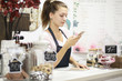 © antgor - Young woman barista using smartphone at bar counter