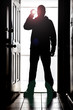 Man standing at door, in silhouette with flashlight