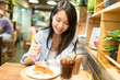 © leungchopan - Woman having cake in coffee shop