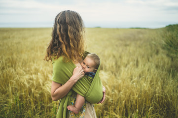 Wall Mural - Mother breastfeeding baby in field