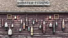 Closeup Of Colorful Floats Hanging Outside A Lobster Fisherman's Cottage. The Image Is Weathered To Add Effect