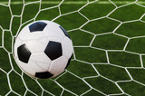 Fototapeta Młodzieżowe - Soccer football in Goal net with green grass field.