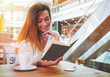 © leszekglasner - Relaxed smiling girl reading book in cafe at shopping mall