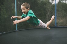 Playful Boy Jumping On Trampoline At Playground