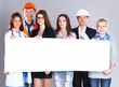 © shefkate - Happy group of people of different professions holding a blank billboard.