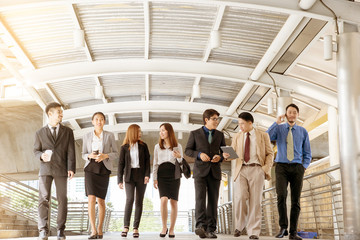 group of happy business people walking in city with sunlight.