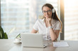 © fizkes - Smiling businesswoman wearing headphones with laptop posing at workplace, happy woman in headset looking at camera while enjoying listening corporate business course, online study, headshot portrait