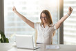 © fizkes - Excited smiling businesswoman celebrating business success at workplace, raising hands looking at laptop screen, feeling happy about great win, good news online, positive result, passed exam, got job