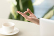 © fizkes - Female hand in chin mudra yogic gesture, peaceful calm woman practices meditation at home office desk with laptop and porcelain cup, yoga at work for relaxation, exercises to reduce stress, close up