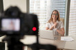 © fizkes - Smiling businesswoman talking on camera, happy entrepreneur vlogger recording business vlog at office desk for videoblog, filming promo ad, making presentation to website, video marketing production