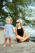 © anoushkatoronto - Group portrait of happy white Caucasian mother and daughter child having fun outside. Mom and child girl playing, hugging in park on pier by water lake. Candid authentic real lifestyle.