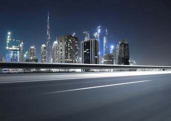 Urban asphalt road with dubai skyline background at night