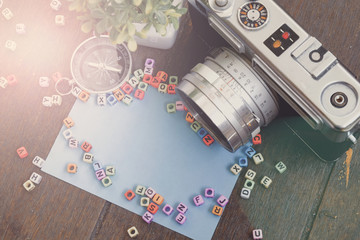 copy space of word block, camera,compass and green plant on wooden background texture and flare effect