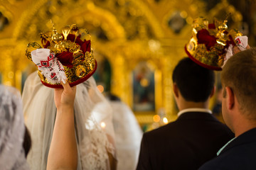 gorgeous bride and stylish groom holding candles at official wedding ceremony in old church. traditional moment