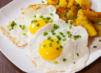 fried eggs with potato in a plate on wooden table