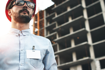 Portrait of young bearded architect man with blank badge or pocket of his shirt