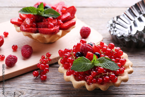 Dessert tartlets with berries on grey wooden table Poster