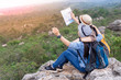 © thitipong - Happy tourists couple holding a map on mountain.