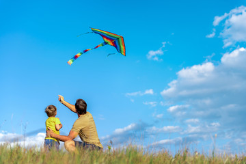 Cheerful boy and man playing with flying toy on field