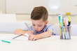 © dobok - child preschooler boy drawing on booklet ,while sitting on the desk in the classroom